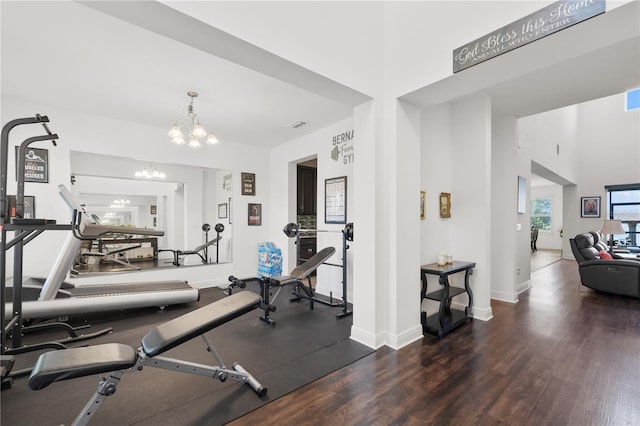 workout area with dark hardwood / wood-style flooring and a notable chandelier