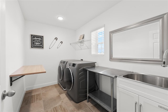 clothes washing area with sink, light tile floors, cabinets, and washer and clothes dryer