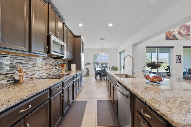 kitchen with decorative light fixtures, tasteful backsplash, stainless steel appliances, and light stone countertops