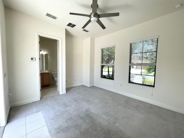 unfurnished bedroom featuring light colored carpet, connected bathroom, and ceiling fan