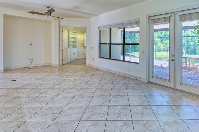 tiled empty room featuring ceiling fan and french doors