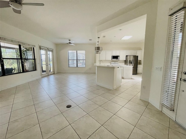 unfurnished living room with ceiling fan, light tile flooring, and sink