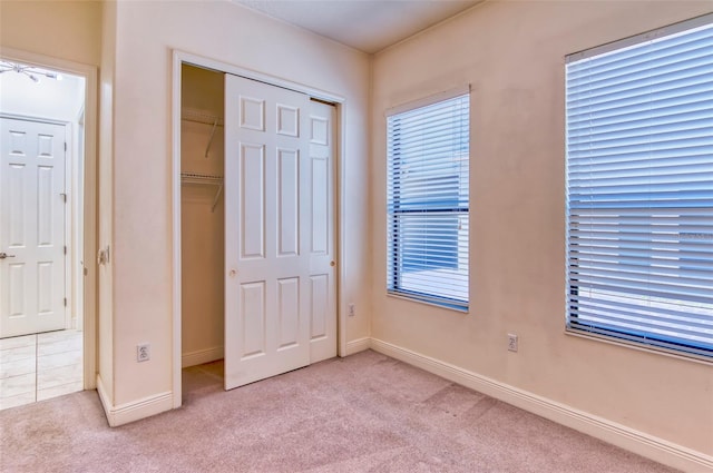 unfurnished bedroom featuring a closet and light colored carpet