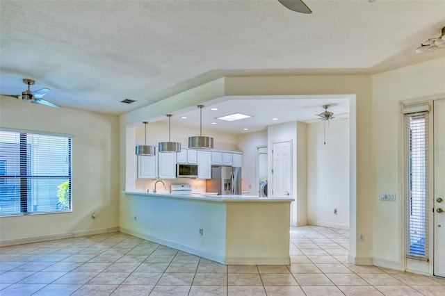 kitchen with ceiling fan, stainless steel appliances, decorative light fixtures, and light tile floors