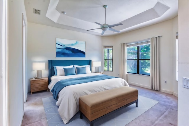 carpeted bedroom featuring ceiling fan and a raised ceiling