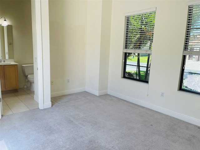 unfurnished bedroom with sink, ensuite bathroom, and light tile floors