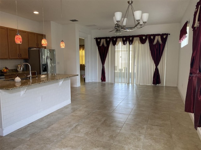 2410 Datura Loop, Saint Cloud, FL 34772 - kitchen featuring stainless steel fridge with ice dispenser, a sink, brown cabinets, stone countertops, and tasteful backsplash
