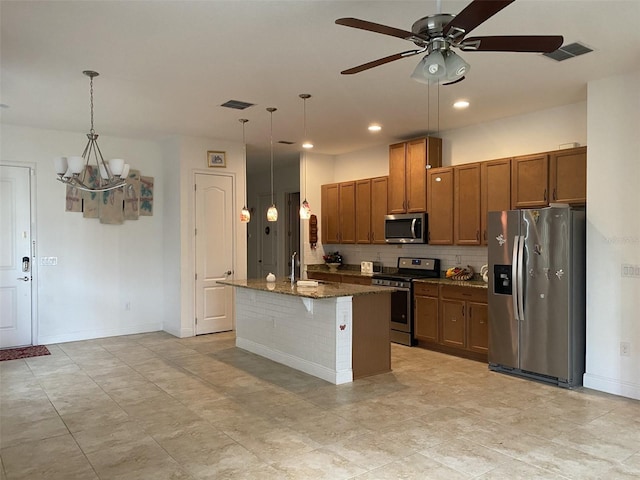 2410 Datura Loop, Saint Cloud, FL 34772 - kitchen with stainless steel appliances, brown cabinetry, tasteful backsplash, a chandelier, and an island with sink
