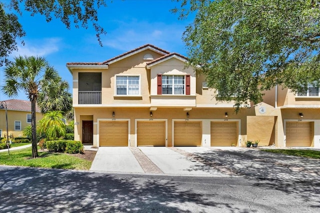 multi unit property featuring stucco siding, driveway, an attached garage, and a tile roof