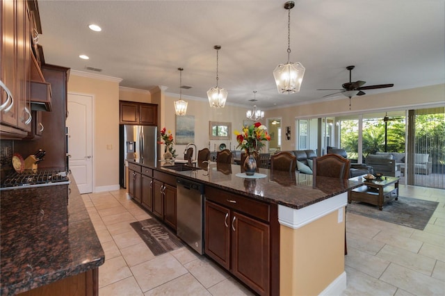 kitchen featuring decorative light fixtures, appliances with stainless steel finishes, ceiling fan with notable chandelier, a kitchen island with sink, and light tile floors