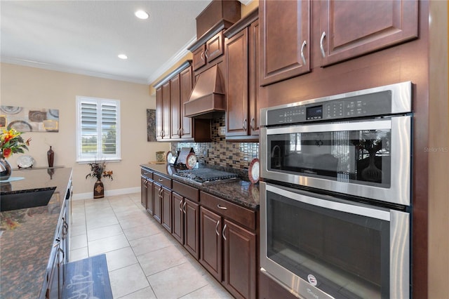 kitchen with stainless steel appliances, tasteful backsplash, custom exhaust hood, dark stone countertops, and ornamental molding