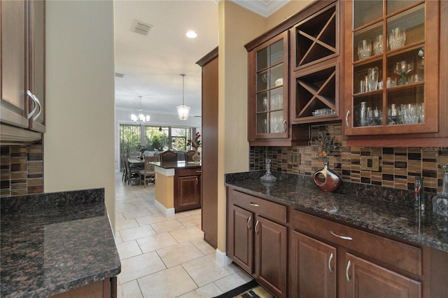 bar featuring backsplash, ornamental molding, pendant lighting, and dark stone counters