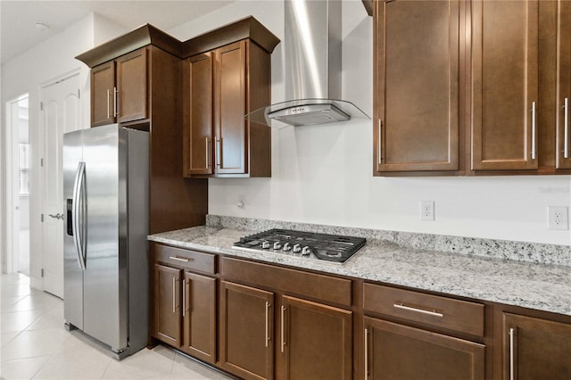 kitchen featuring appliances with stainless steel finishes, light stone countertops, light tile flooring, and wall chimney exhaust hood