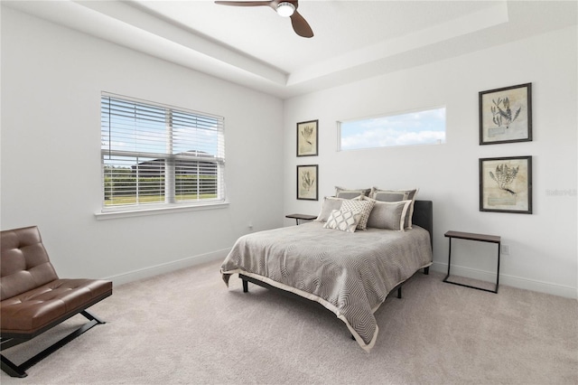 carpeted bedroom featuring a raised ceiling and ceiling fan