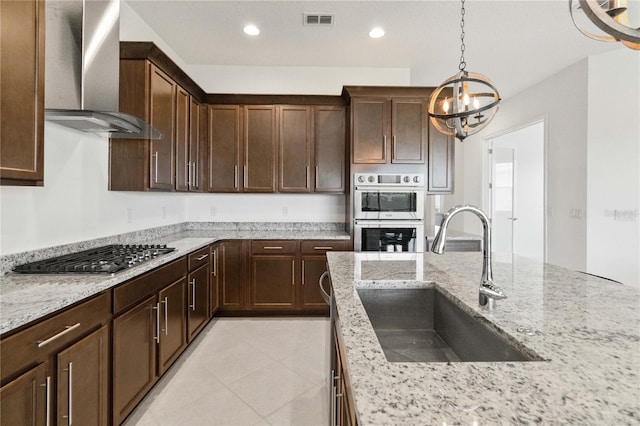 kitchen with sink, light stone countertops, wall chimney range hood, and light tile floors