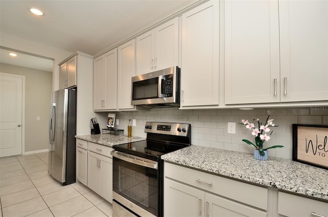 kitchen featuring decorative backsplash, light tile patterned floors, light stone counters, and appliances with stainless steel finishes