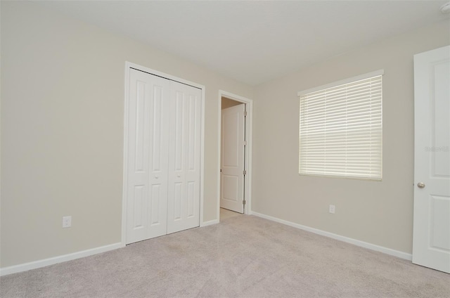 unfurnished bedroom with a closet and light colored carpet