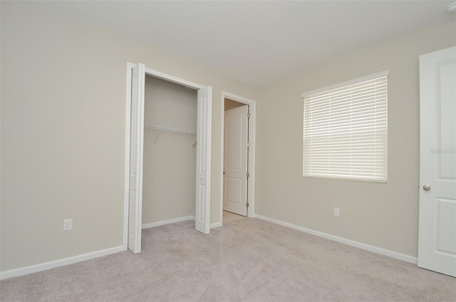 unfurnished bedroom featuring a closet and light colored carpet