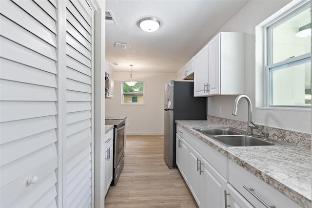 kitchen with pendant lighting, white cabinets, stainless steel electric range, sink, and light hardwood / wood-style floors