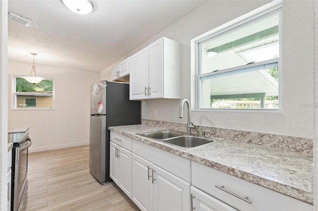 kitchen with decorative light fixtures, sink, a healthy amount of sunlight, and electric range