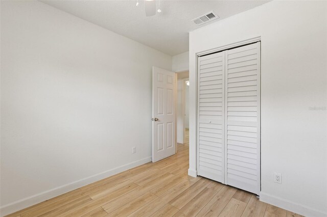 unfurnished bedroom with light hardwood / wood-style floors, ceiling fan, a closet, and a textured ceiling