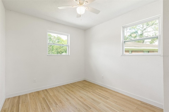 empty room featuring plenty of natural light, ceiling fan, and light hardwood / wood-style flooring