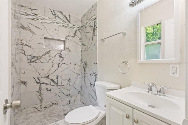 bathroom featuring vanity, toilet, and a tile shower