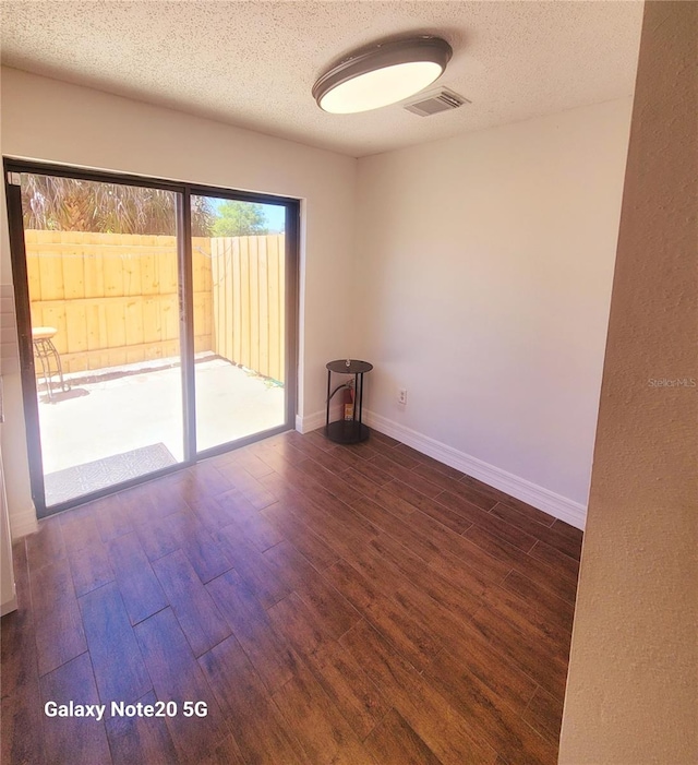 unfurnished room featuring a textured ceiling and dark hardwood / wood-style flooring