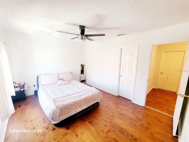 bedroom with light hardwood / wood-style flooring, ceiling fan, and a textured ceiling