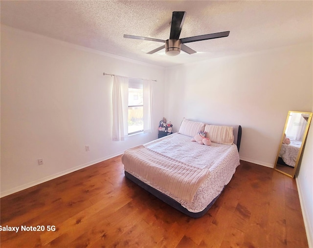 bedroom with dark hardwood / wood-style floors, ceiling fan, and a textured ceiling