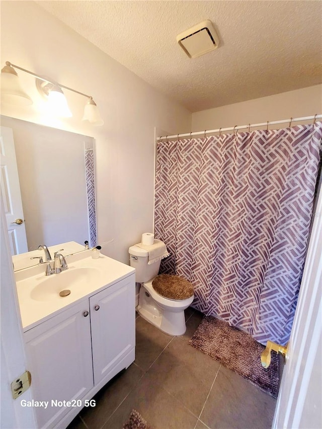 bathroom with tile flooring, vanity, toilet, and a textured ceiling