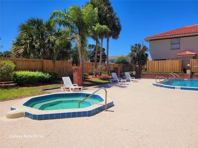 view of swimming pool with a patio and an outdoor hot tub