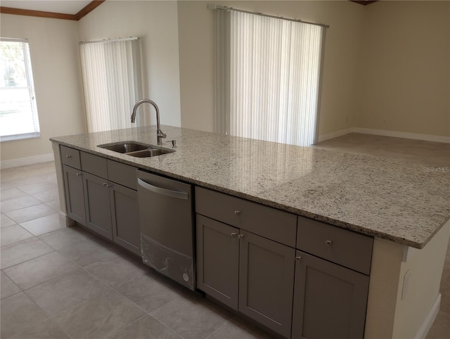 kitchen with light tile flooring, stainless steel dishwasher, sink, and light stone countertops