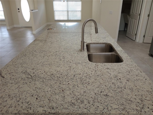 kitchen featuring sink, light tile floors, and light stone countertops