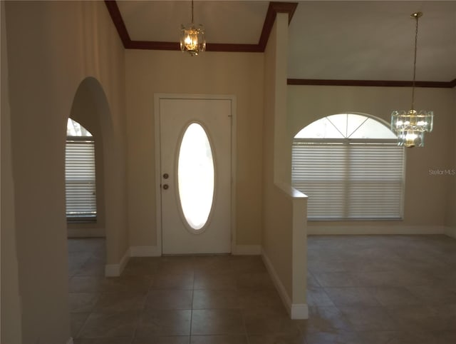 tiled entrance foyer featuring a chandelier, a towering ceiling, and crown molding