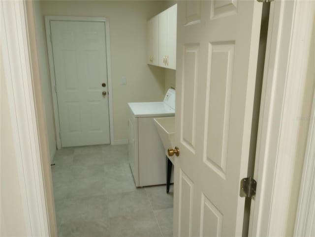 clothes washing area with independent washer and dryer, cabinets, and light tile flooring