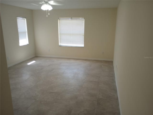 tiled empty room featuring ceiling fan