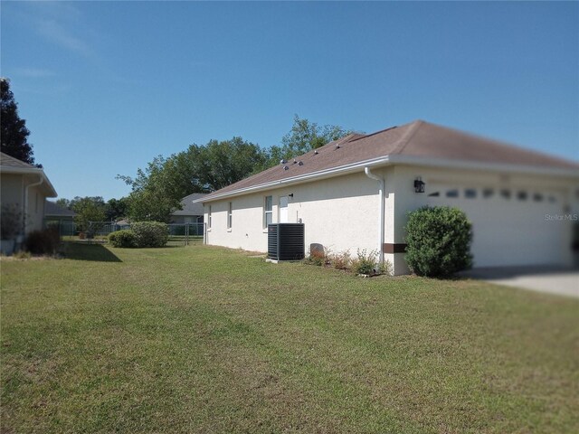 view of side of property with central AC unit and a yard