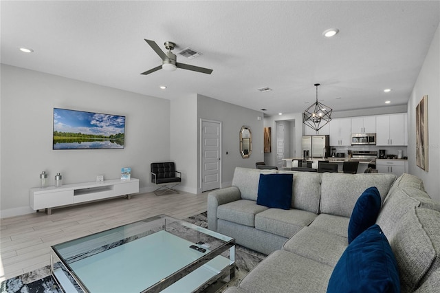 living room featuring light hardwood / wood-style floors and ceiling fan with notable chandelier