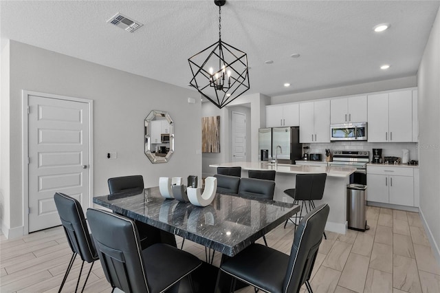 dining room featuring a notable chandelier, sink, and a textured ceiling