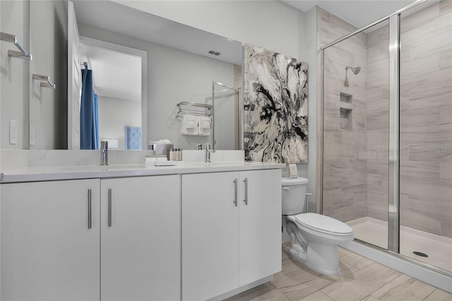 bathroom featuring a shower with door, large vanity, toilet, tile floors, and dual sinks