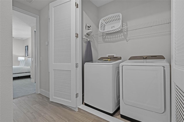 washroom with light hardwood / wood-style flooring and washing machine and clothes dryer