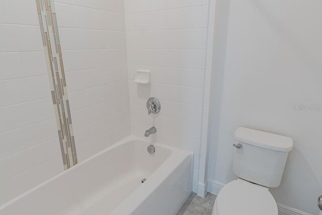 bathroom featuring tile flooring, tiled shower / bath combo, and toilet