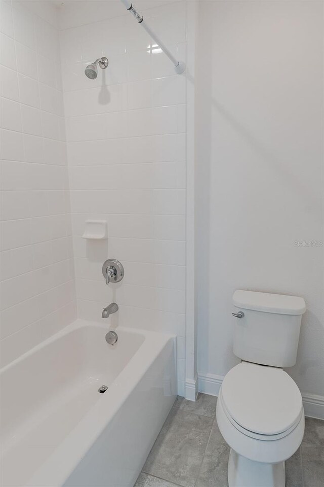 bathroom with tile floors, toilet, and tiled shower / bath