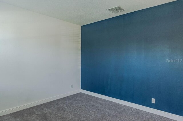 carpeted empty room featuring a textured ceiling