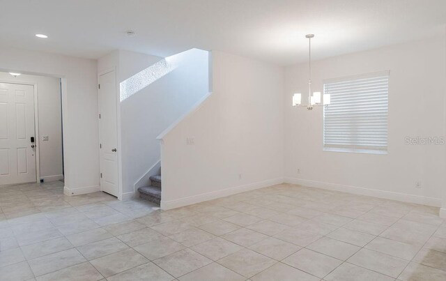 empty room featuring light tile floors and an inviting chandelier