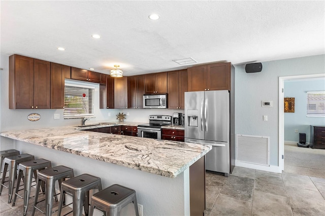 kitchen featuring kitchen peninsula, light colored carpet, appliances with stainless steel finishes, sink, and a breakfast bar