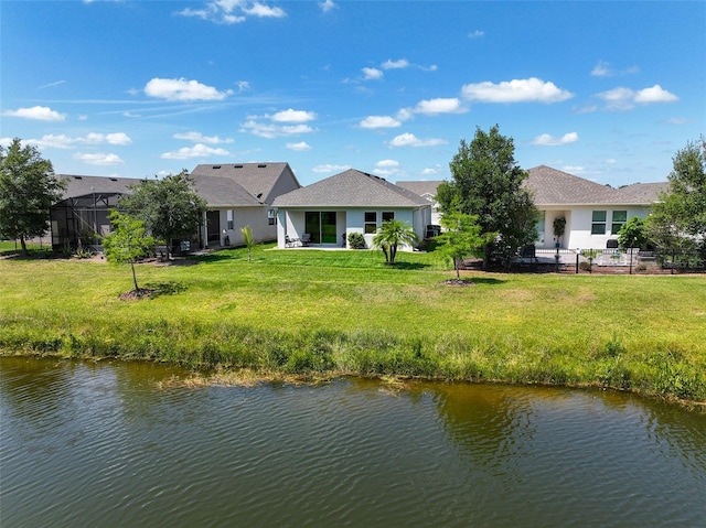 back of property with a water view and a lawn