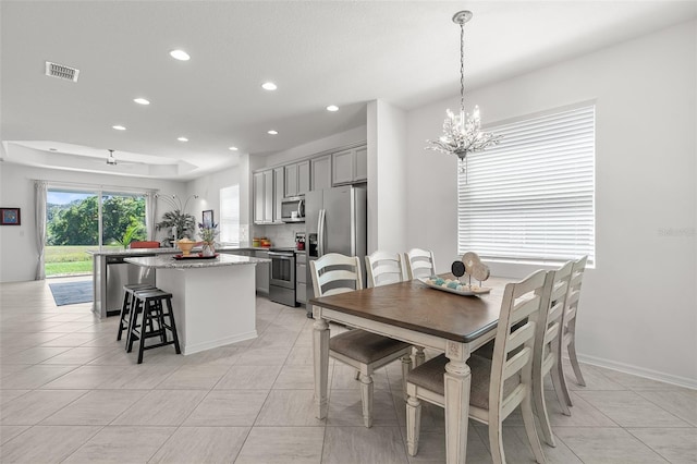 tiled dining area with a raised ceiling and an inviting chandelier