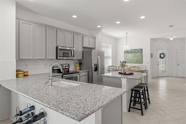 kitchen featuring a center island, pendant lighting, backsplash, stainless steel appliances, and a breakfast bar area